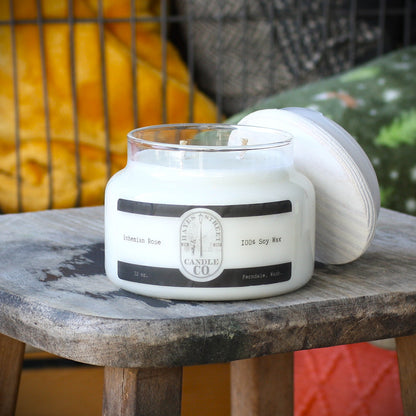 A jar candle labeled 'Bohemian Rose' by Hayes Street Candle Co. sits on a rustic wooden table, with its white lid leaning against the jar.