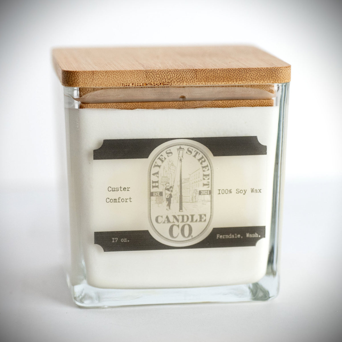 A square glass jar candle with white wax and a light bamboo wood lid, featuring a vintage-style cream and black label from Hayes Street Candle Co.