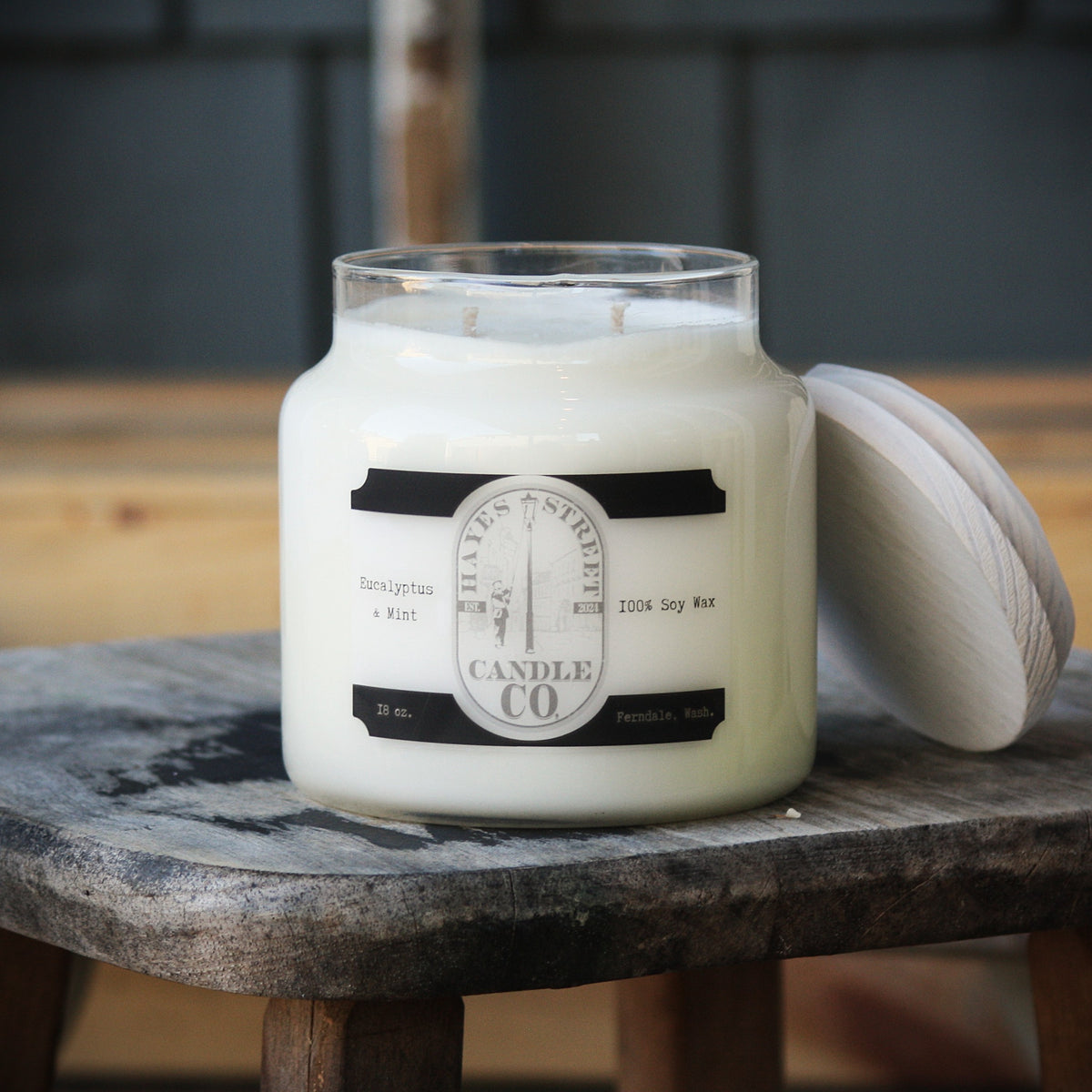 Eucalyptus and Mint soy wax candle from Hayes Street Candle Company. It is double wicked and in an apothecary-style jar with a wooden lid leaning against the side of it. This candle burns for approximately 70 hours.