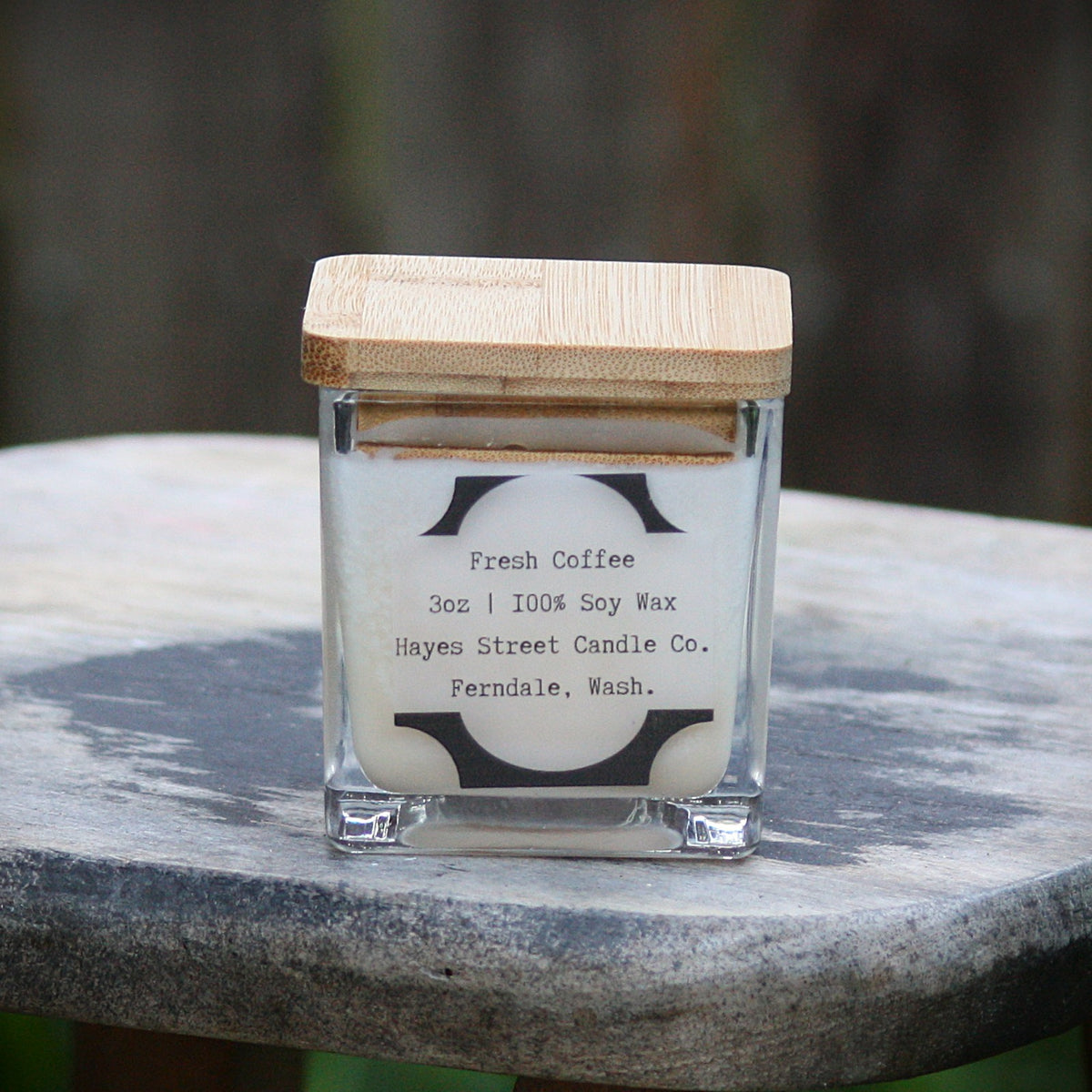 Another angle of Fresh Coffee small square candle jar from Hayes Street Candle Co. This one is a square jar made of glass with a bamboo wooden lid on top.