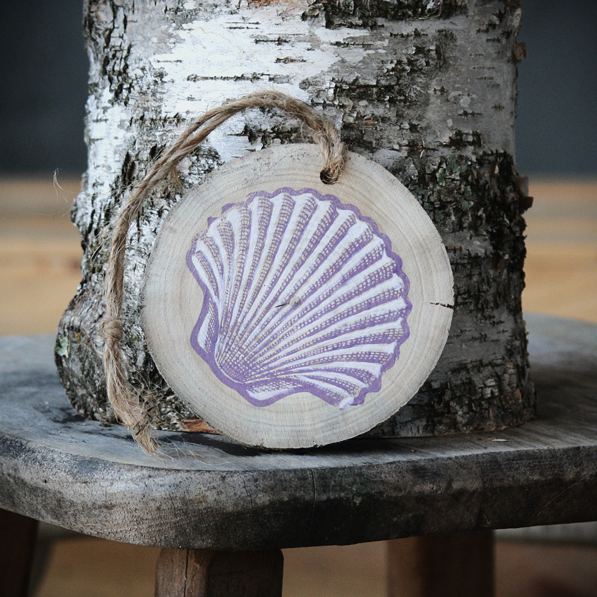 Driftwood log slice with a purple and white seashell stamped on it