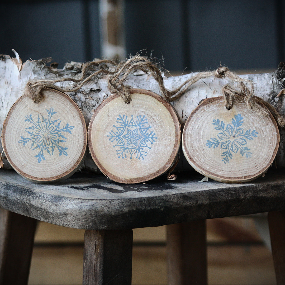 Three snowflake ornaments on birch wood from Log Slices by Margie and Hayes Street Candle Company.