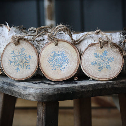 Three snowflake ornaments on birch wood from Log Slices by Margie and Hayes Street Candle Company.
