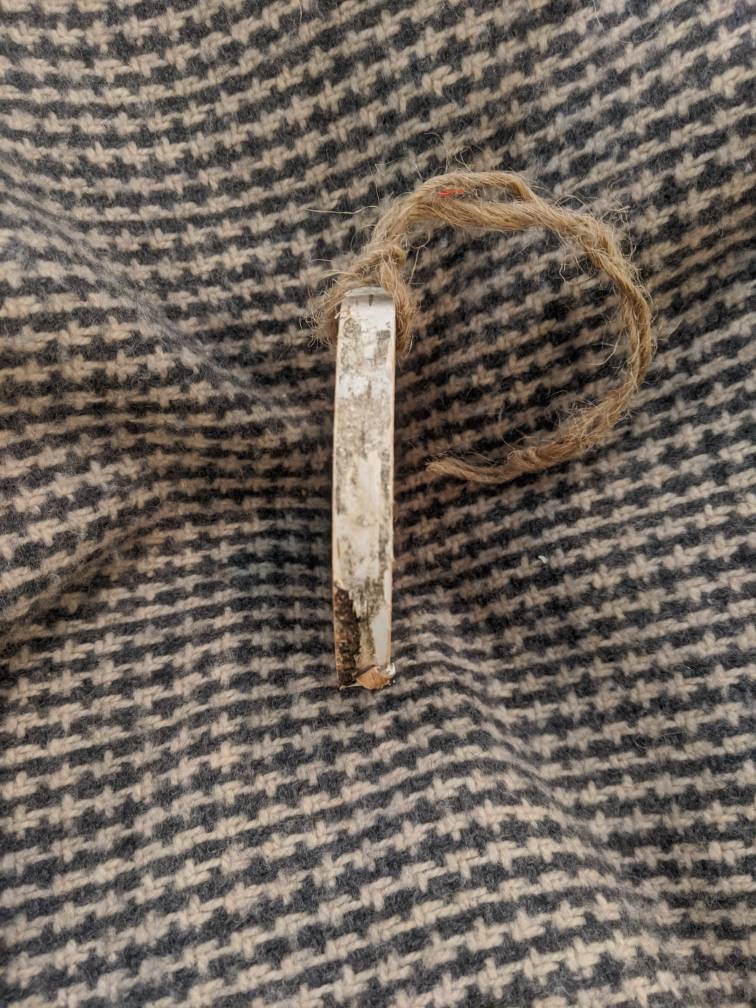 Wood ornament with twine on a textured fabric background
