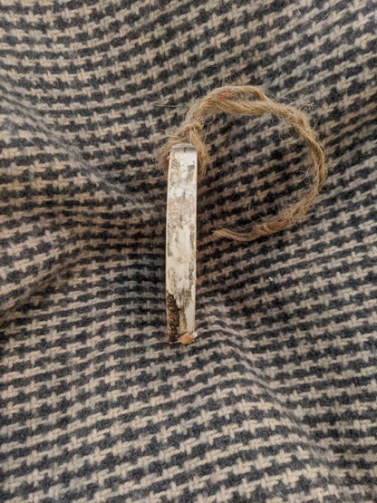 Wood ornament with twine on a textured fabric background